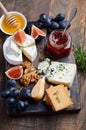 Cheese plate with grapes, figs, crackers, honey, plum jelly, thyme and nuts.