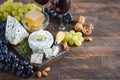 Cheese plate with grapes, honey, nuts and red wine on a wooden table. Royalty Free Stock Photo