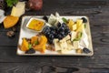 Cheese plate with grapes, honey, prunes and walnuts. Cold appetizer for wine from several types of different moldy cheeses in a ce Royalty Free Stock Photo