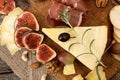 Cheese plate with pieces moldy cheese, prosciutto, pickled plums Royalty Free Stock Photo