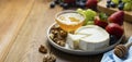 Cheese plate round sliced soft cheese, blueberry, strawberry, grapes and honey on wooden table. Banner Royalty Free Stock Photo