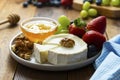 Cheese plate round sliced soft cheese, blueberry, strawberry, grapes and honey on wooden table Royalty Free Stock Photo