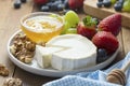 Cheese plate round sliced soft cheese, blueberry, strawberry, grapes and honey on wooden table Royalty Free Stock Photo