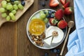 Cheese plate round sliced soft cheese, blueberry, strawberry, grapes and honey on wooden table, flat lay Royalty Free Stock Photo