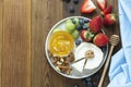 Cheese plate round sliced soft cheese, blueberry, strawberry, grapes and honey on wooden table, flat lay Royalty Free Stock Photo