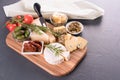 Cheese plate with selection of cheeses served with olives, tomatoes and herbs at gray table Royalty Free Stock Photo