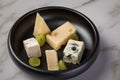 Cheese plate with selection Edamer, Parmesan, goat, blue and cream cheese, peer and grapes on black dish and marble background