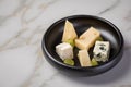 Cheese plate with selection Edamer, Parmesan, goat, blue and cream cheese, peer and grapes on black dish and marble background