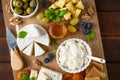 Cheese plate with a variety of cheeses, honey, grapes, nuts, olives, blueberries and fresh herbs on a dark wooden background. Royalty Free Stock Photo