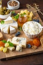 Cheese plate with a variety of cheeses, honey, grapes, nuts, olives, blueberries and fresh herbs on a dark wooden background. Royalty Free Stock Photo