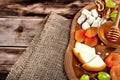 Cheese plate - various types of cheese, honey, grapes, dried apricots, nuts and figs on a wooden board.