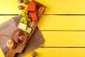 Cheese plate - various types of cheese, honey, grapes, dried apricots, nuts and figs on a wooden board on yellow wooden.