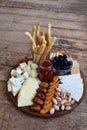 Cheese plates served with grissini, crackers, dates, jam, olives and nuts on wooden background. Cheese board. Snack to wine Royalty Free Stock Photo