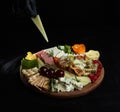 Cheese platter. Appetizers boards with assorted cheese, honey, grapes and nuts. Chef\'s hand adds a piece
