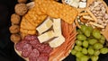 Cheese platter with assorted cheeses, grapes, nuts over black background Royalty Free Stock Photo