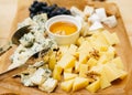 Cheese platter with blue cheese, honey and grapes on wooden table Royalty Free Stock Photo