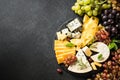 Cheese platter with craft cheese assortment at black background.