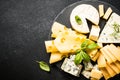 Cheese platter with craft cheese assortment on slate board at black background. Royalty Free Stock Photo