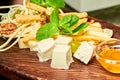 Cheese platter with feta, parmesan, mozzarella, cheese sticks, braid cheese with honey and nuts on the wooden board