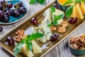 Cheese platter garnished with honey, walnuts, grapes, bread, mint and glass of wine