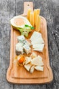 Cheese platter garnished with pear, honey, carambola, physalis on cutting board on wooden background. Snacks and Wine appetizers Royalty Free Stock Photo