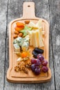 Cheese platter garnished with pear, honey, walnuts, grapes, carambola, physalis on cutting board on wooden background Royalty Free Stock Photo