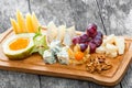 Cheese platter garnished with pear, honey, walnuts, grapes, carambola, physalis on cutting board on wooden background. Royalty Free Stock Photo