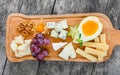 Cheese platter garnished with pear, honey, walnuts, grapes, carambola, physalis on cutting board on wooden background Royalty Free Stock Photo