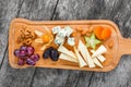 Cheese platter garnished with pear, honey, walnuts, grapes, carambola, physalis on cutting board on wooden background Royalty Free Stock Photo