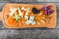 Cheese platter garnished with pear, honey, walnuts, grapes, carambola, physalis on cutting board on wooden background Royalty Free Stock Photo