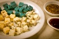 Cheese platter, Gouda, feta, blue pesto cheeses on white plate with herbs, olive oil, pomegranate and mustard sauces Royalty Free Stock Photo