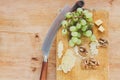 Cheese platter, sliced cheese on natural wood board with grapes