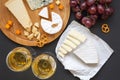 Cheese platter with wine, fruits, pretzels and walnuts on dark background, from above. Royalty Free Stock Photo