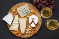 Cheese platter with wine, grapes, pretzels and walnuts on dark background, from above.Top view.