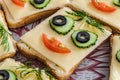 Sandwich with face from cucumbers, tomato, olives and dill