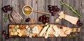 Cheese selection on wooden rustic board. Cheese platter with different cheeses, grapes, nuts, honey and dates on weathered wood b Royalty Free Stock Photo