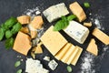 Cheese set: brie, blue cheese, parmesan and basil on a black concrete background. View from above Royalty Free Stock Photo