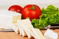 Cheese slices, tomatoes and lettuce leaf for breakfast on a board.