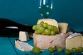 Cheese, grapes and wine on wooden cyan surface.