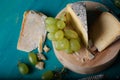 Cheese, grapes and wine on wooden cyan surface.