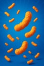 Cheese snacks in motion against a vibrant blue background, creating a playful and appetizing scene Royalty Free Stock Photo
