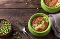 Cheese souffle with young peas flavored with thyme in portion molds on a wooden table