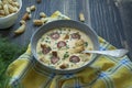 Cheese soup with grilled sausages and herbs. Cream soup served in a plate. Dark wooden background Royalty Free Stock Photo