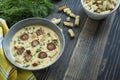 Cheese soup with grilled sausages and herbs. Cream soup served in a plate. Dark wooden background Royalty Free Stock Photo