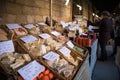 Cheese stall with shoppeers customers at a food market in cathedral cloisters showing people, goods and stalls