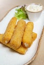 Cheese sticks fried in breadcrumbs. Mozzarella cheese sticks on a plate with sauce and lettuce Royalty Free Stock Photo
