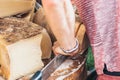 cheese trader in the market cuts a large piece of cheese