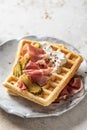 Cheese waffles with ham, cream cheese and cucumber close up. Delisious savory breakfast