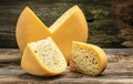 Cheese wheel with cut a piece of cheese triangular shape from a large cheese head. cheese maasdam with big holes on a wooden Royalty Free Stock Photo