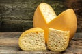 Cheese wheel with cut a piece of cheese triangular shape from a large cheese head. cheese maasdam with big holes on a wooden Royalty Free Stock Photo